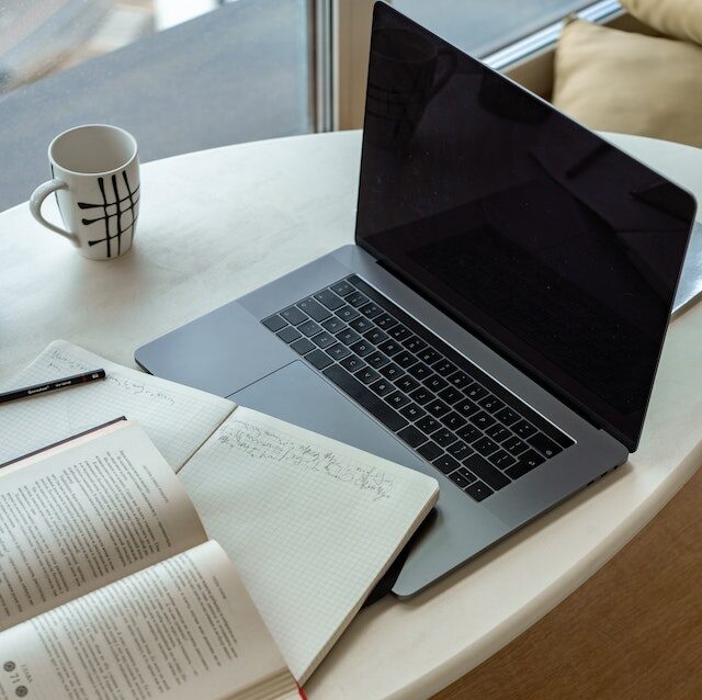 Computer, book, and notebook on desk alone