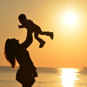 Mother Lifting baby on the beach at sunset