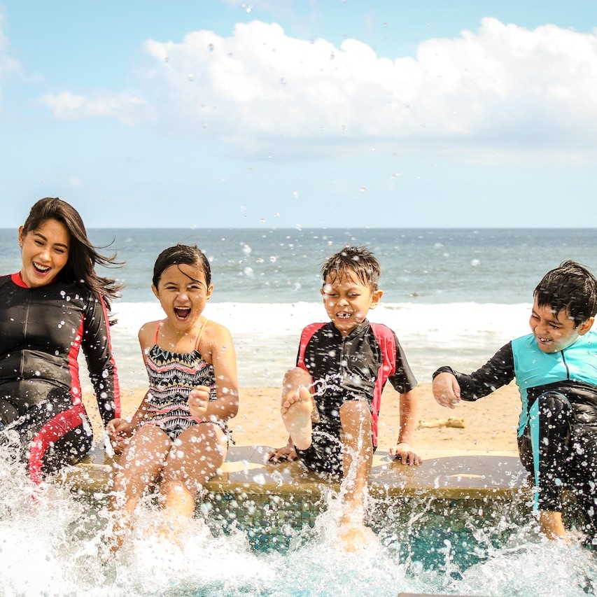 Mother with 3 children kicking water and laughing