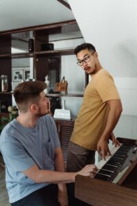 Gay couple looking each other over a piano