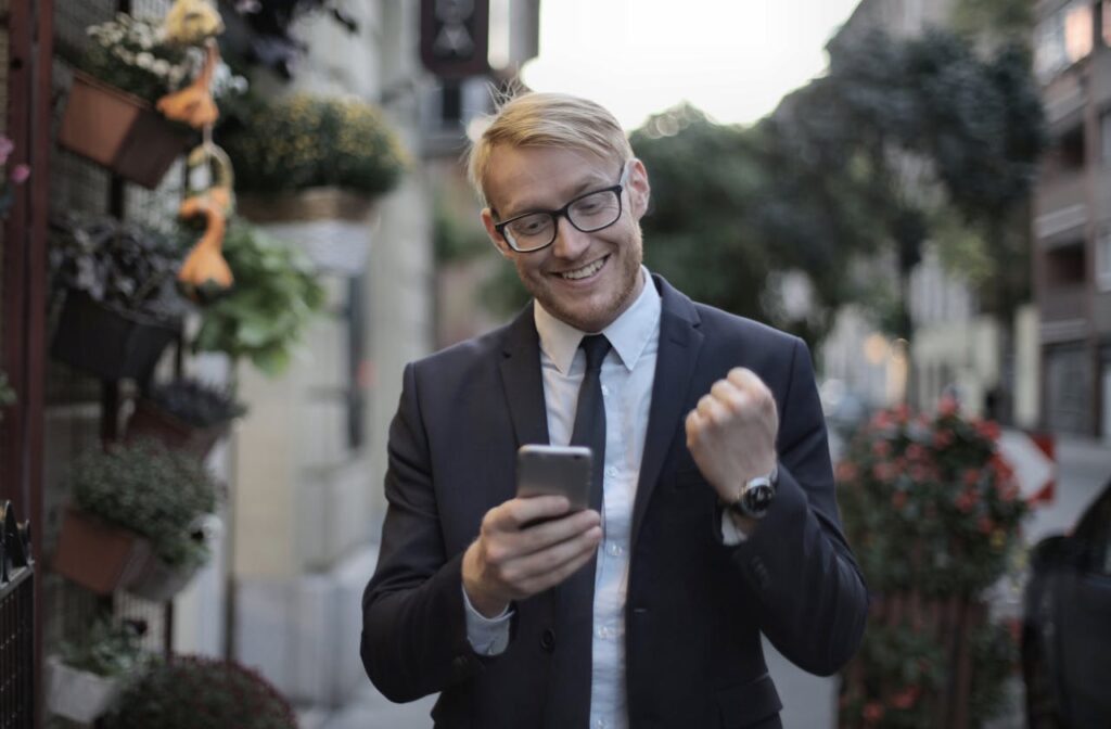 White man in a suit happy with his celphone