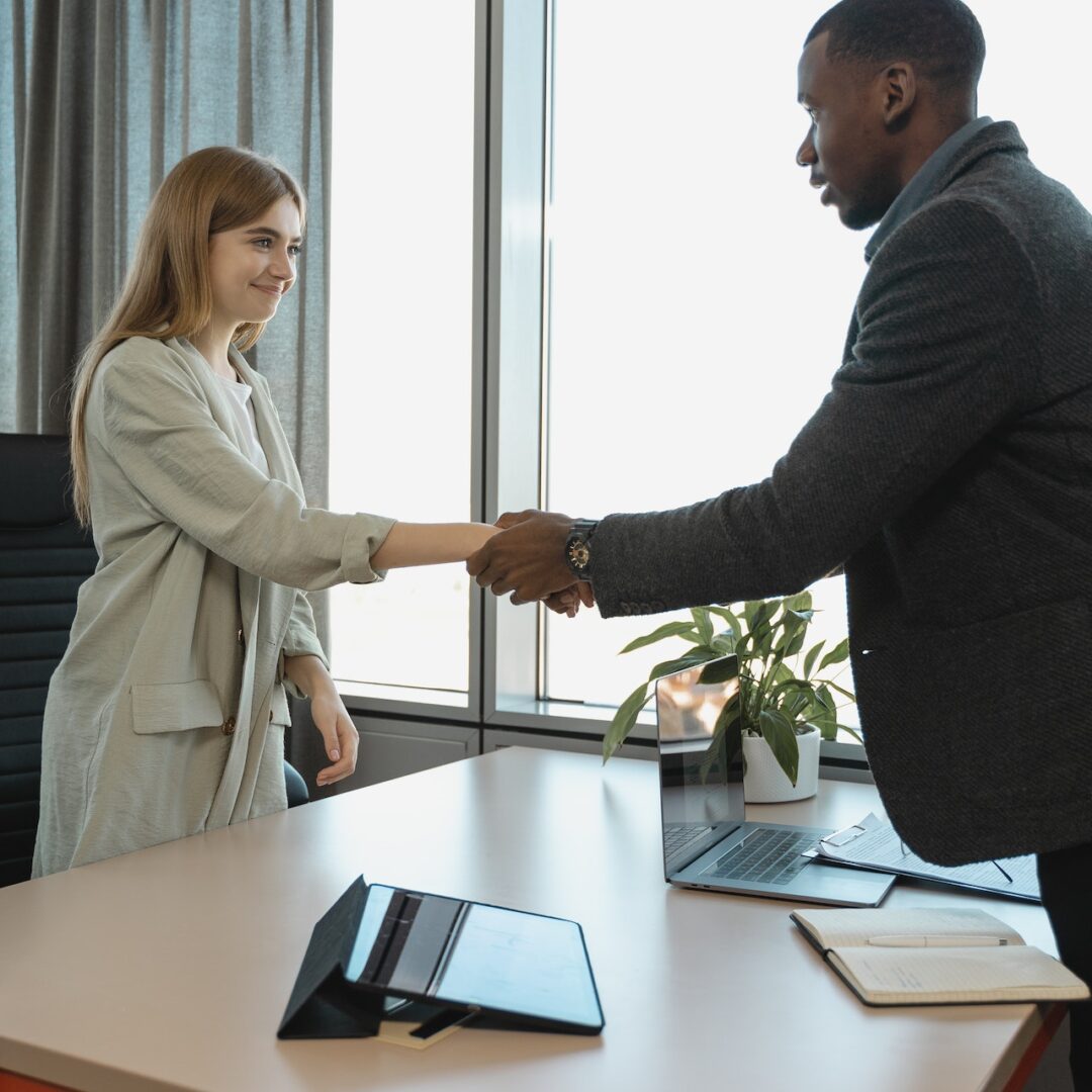 Black man in a suit handshaking a young woman